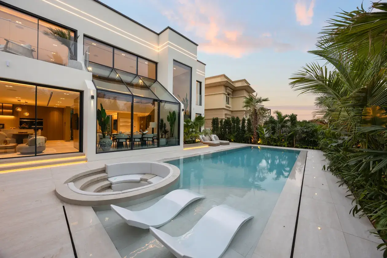 Swimming pool with in-water loungers and sunken seating at sunset, luxury villa in Jumeirah Islands, Dubai.
