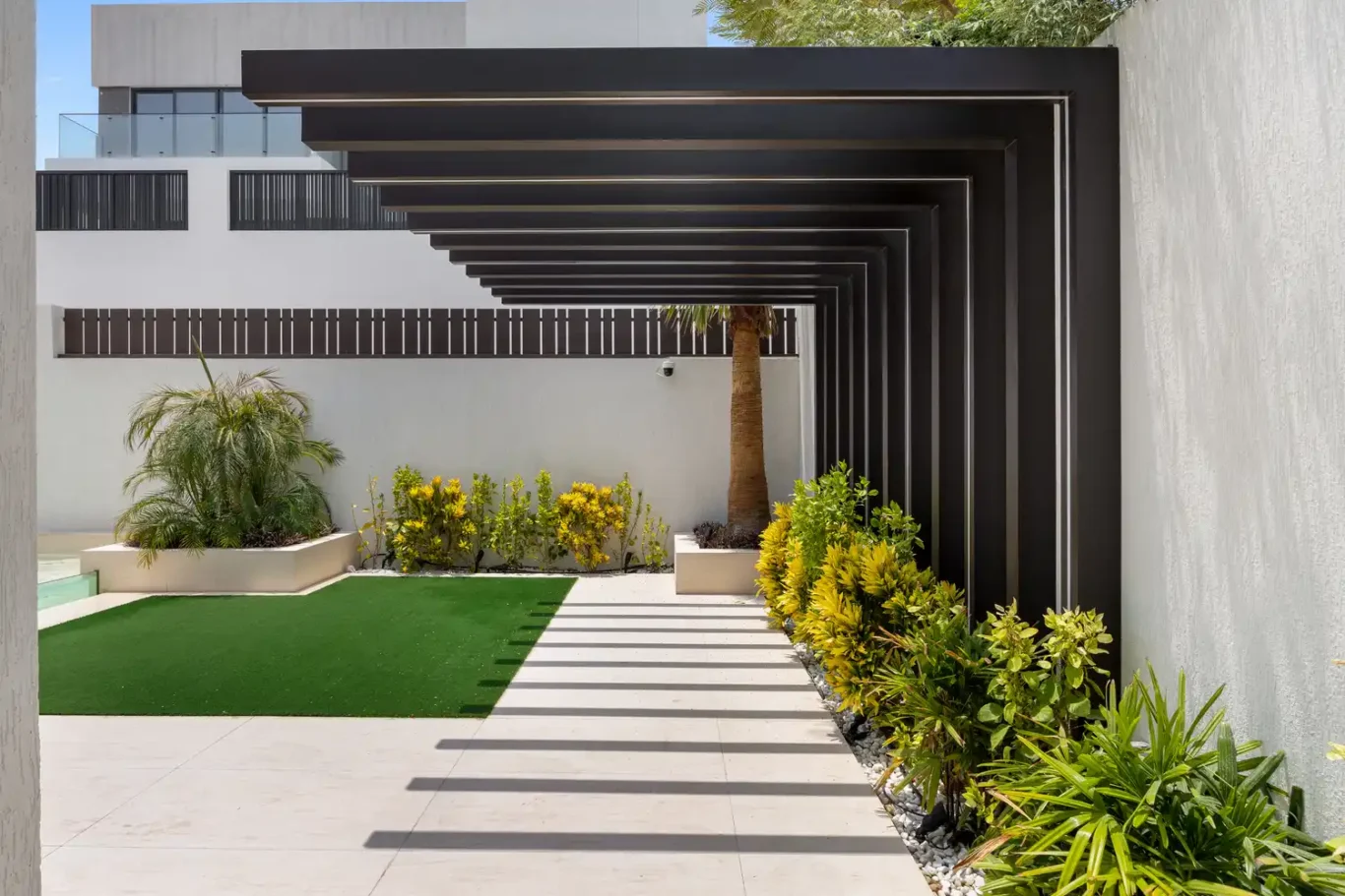 Garden path under a dark pergola, unfurnished five-bedroom villa in Al Furjan, Dubai.