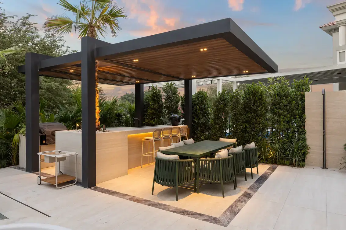 Outdoor kitchen and dining pergola lit at dusk, luxury villa in Jumeirah Islands, Dubai.