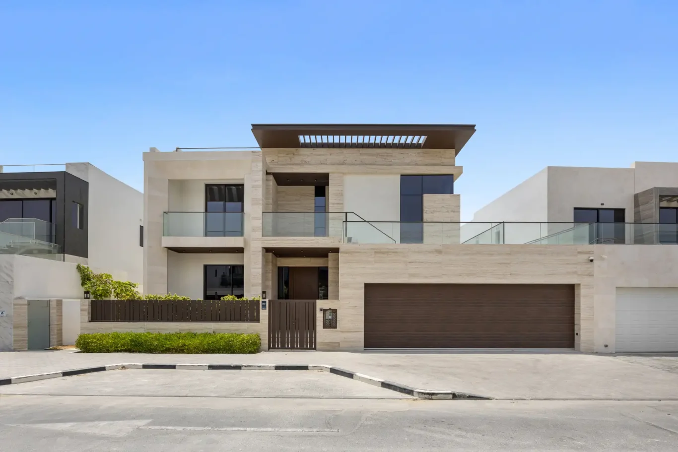 Front facade with travertine cladding and garage doors, unfurnished five-bedroom villa in Al Furjan, Dubai.