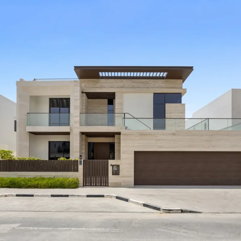 Front facade with travertine cladding and garage doors, unfurnished five-bedroom villa in Al Furjan, Dubai.