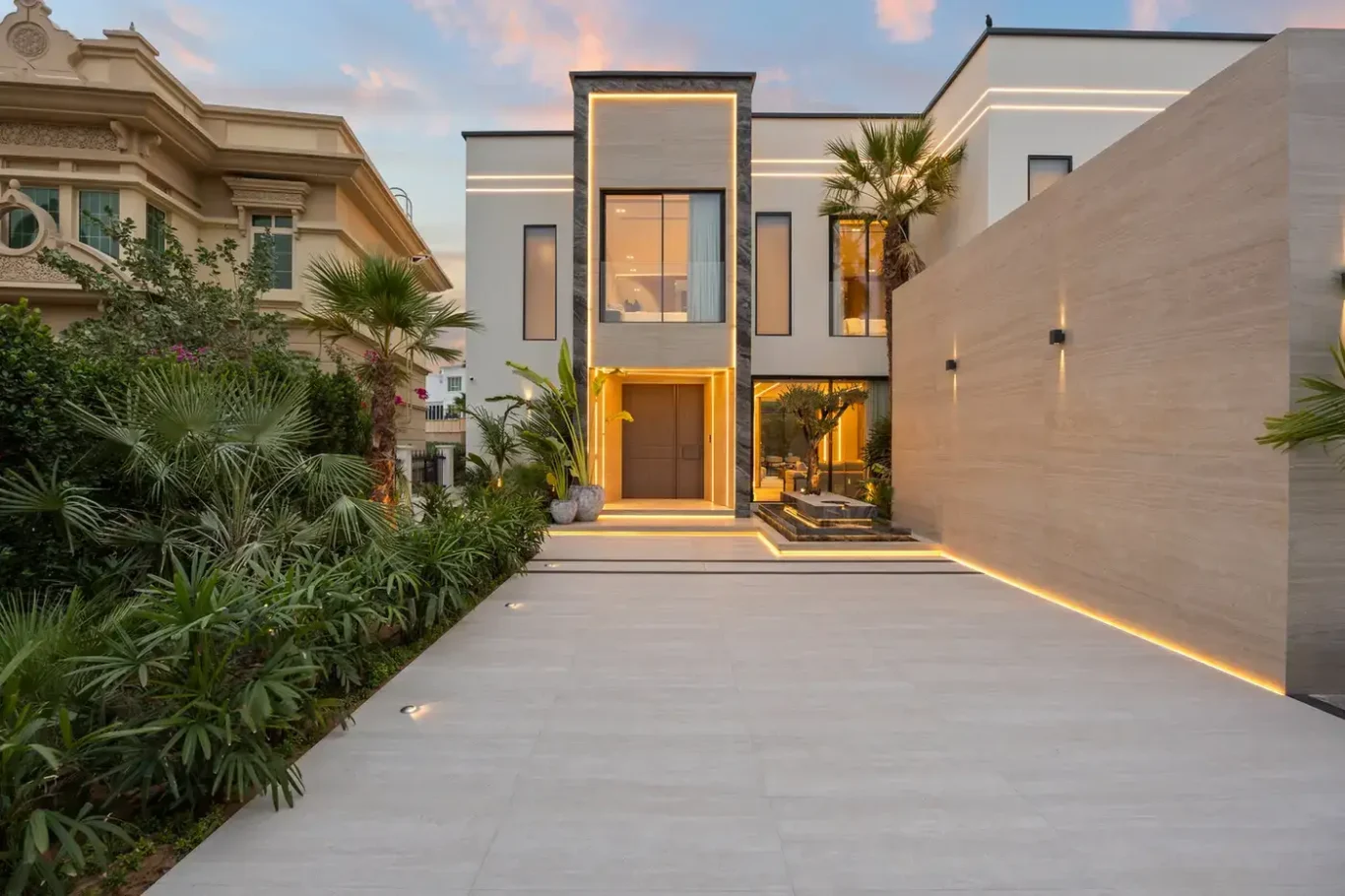 Illuminated front entrance and stone wall at dusk, luxury villa in Jumeirah Islands, Dubai.