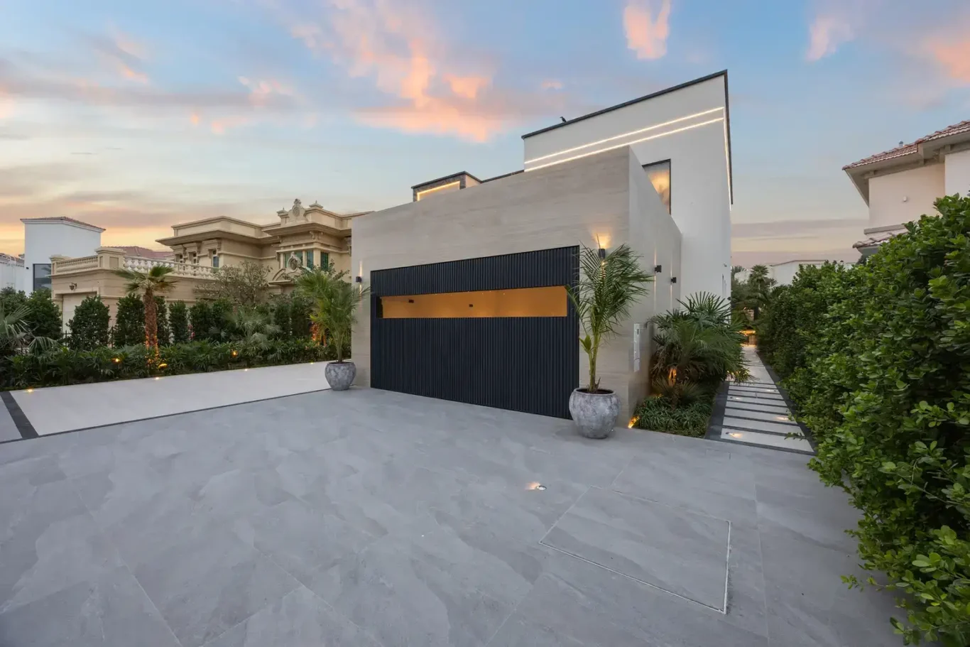 Garage with lit windows and the driveway at dusk, luxury villa in Jumeirah Islands, Dubai.