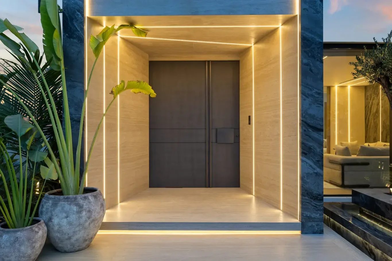 Illuminated front door framed in stone at dusk, luxury villa in Jumeirah Islands, Dubai.